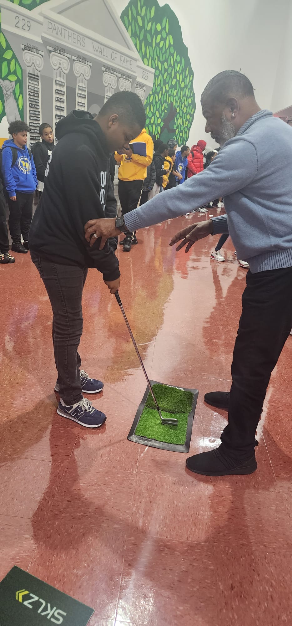 Miguel Martinez coaching a student's golf stance as part of Golf as an Etiquette Sport